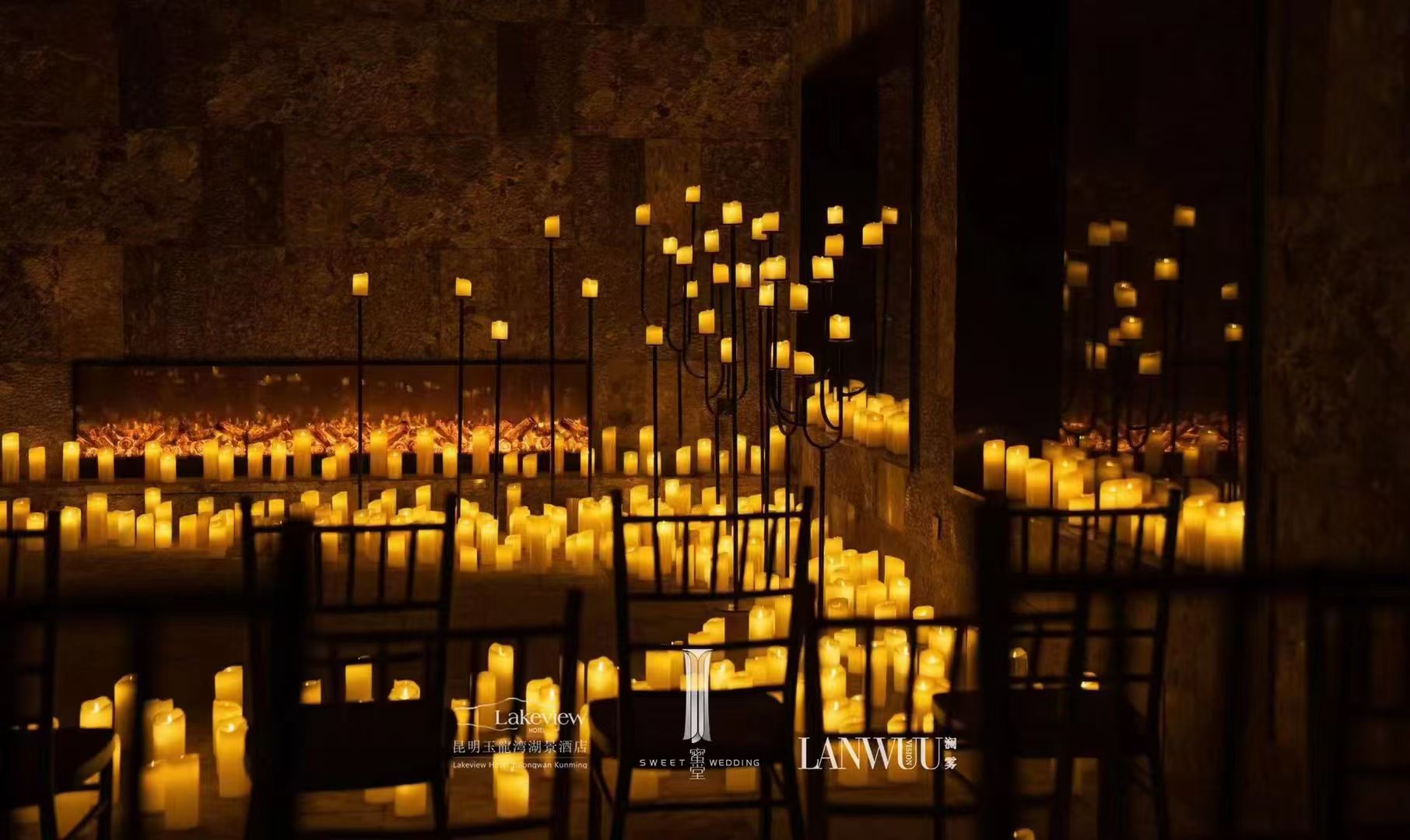 Warm LED pillar candles arranged along an event venue fireplace and on tall candle stands