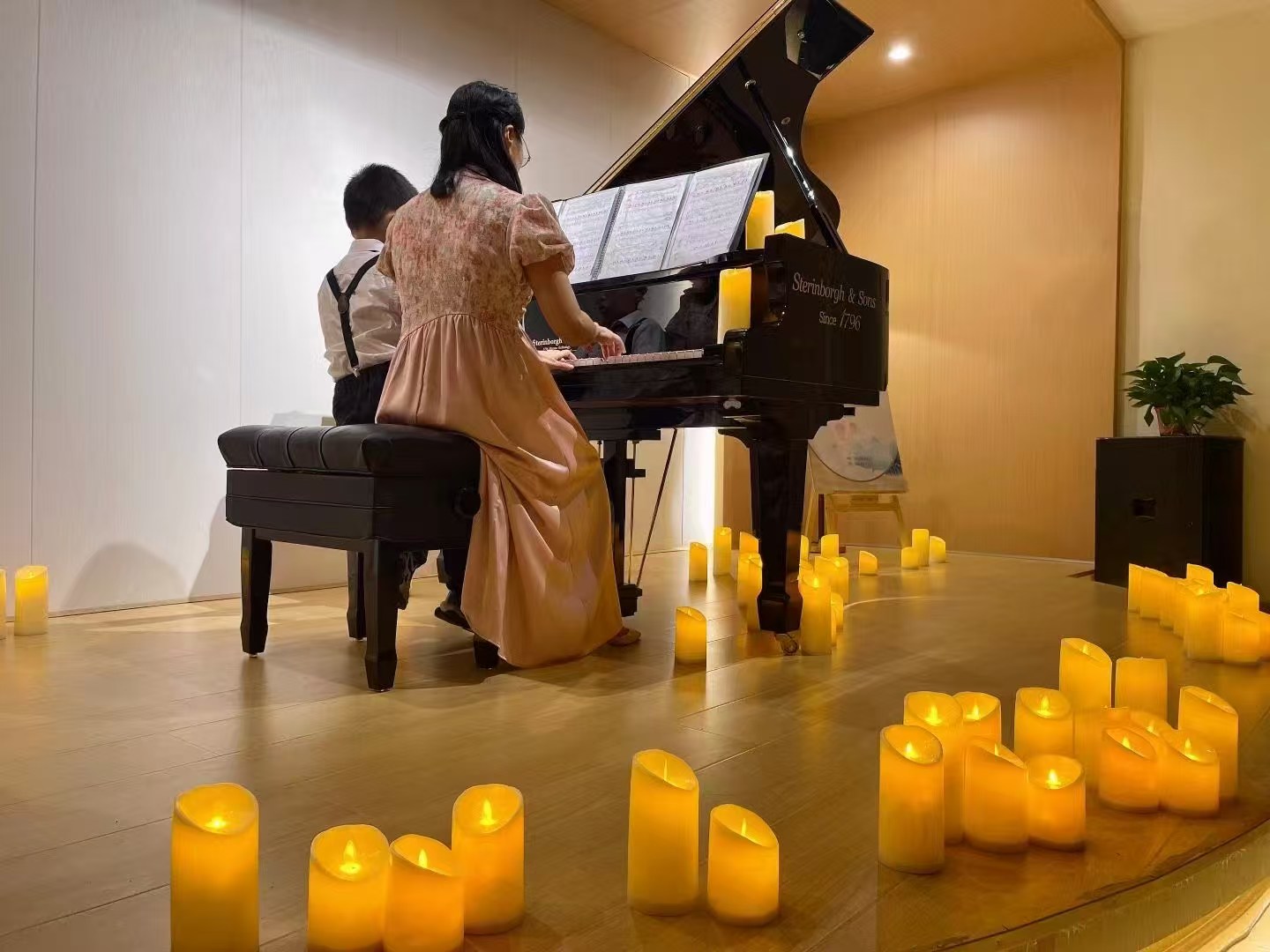 LED pillar candles arranged around a grand piano during a live performance