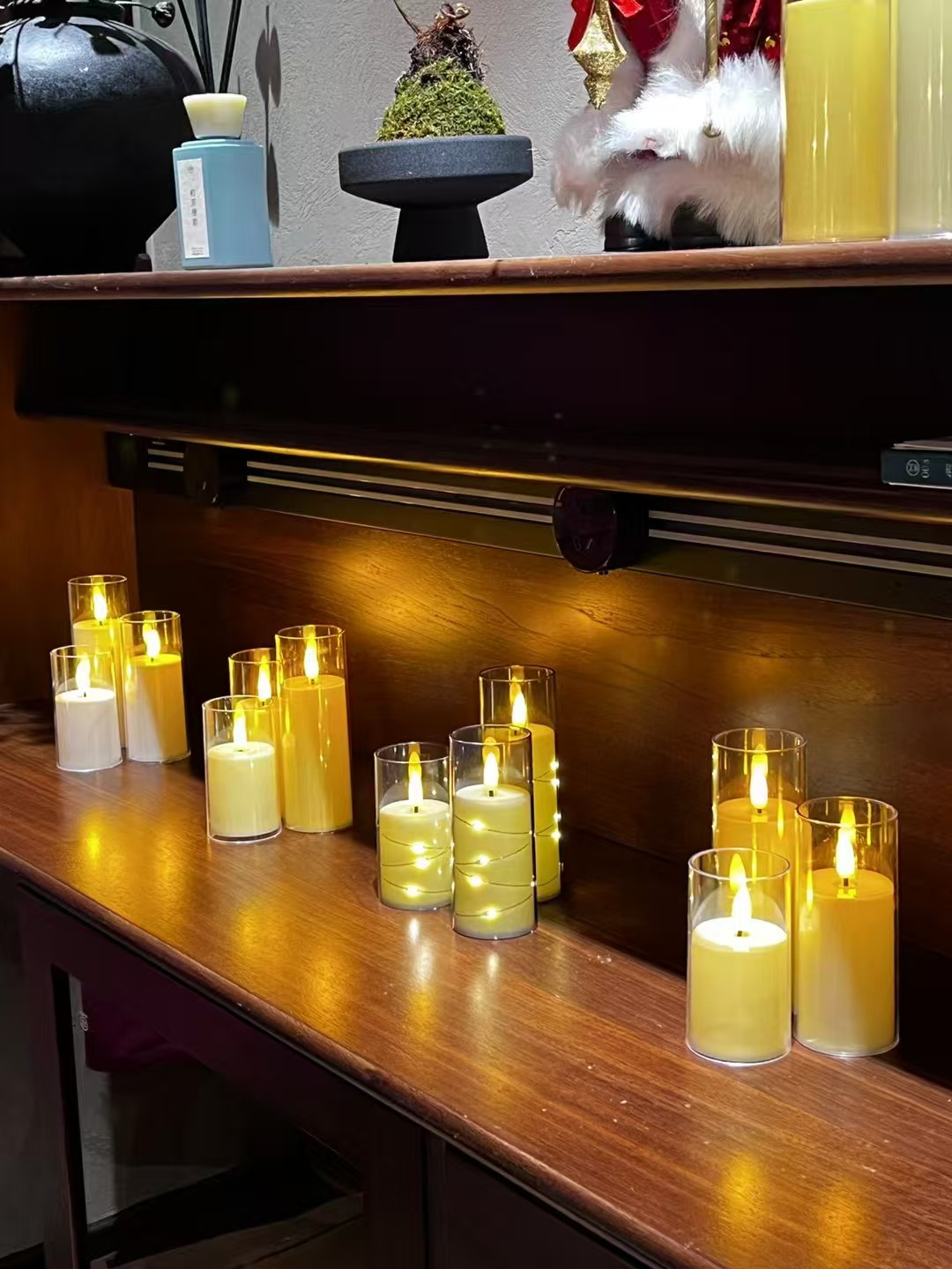 Groups of glass-enclosed LED pillar candles in several heights on a wooden counter
